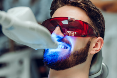 dentist doing teeth whitening treatment on a male patient