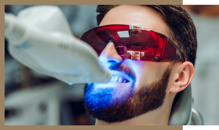 dentist doing a whitening dental treatment on a male patient