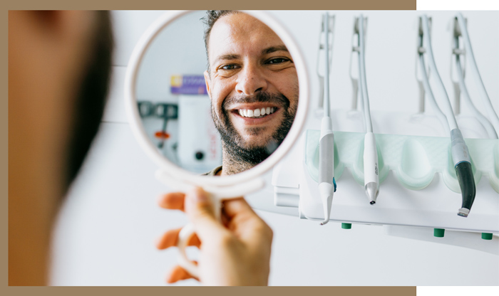 male patient smiling into mirror at dental practice